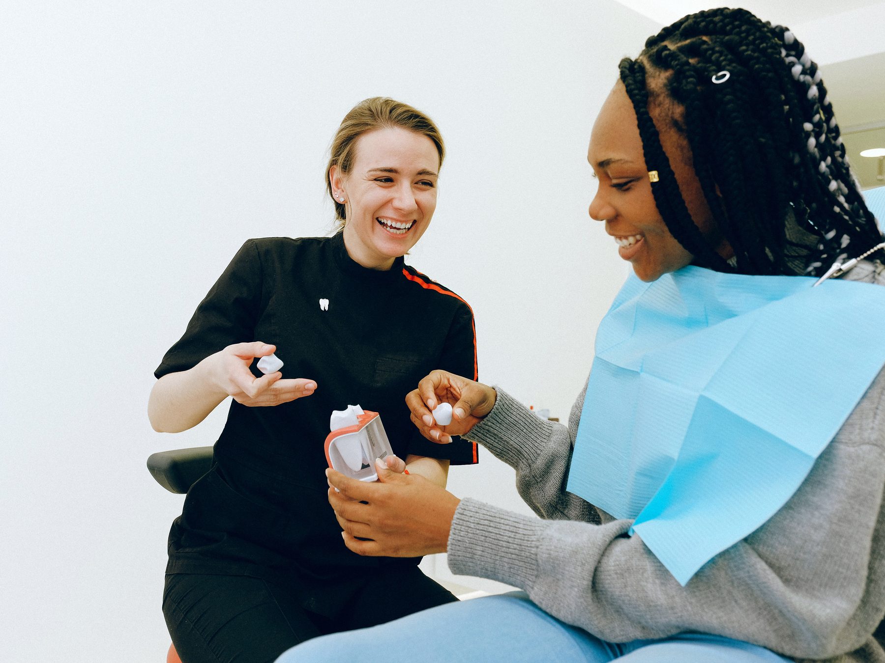 A dentist and a patient laughing together during a visit