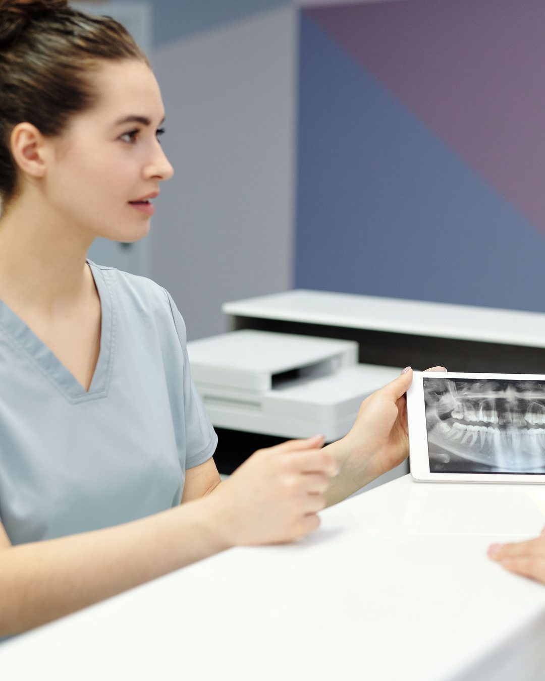 A dental team member going over an X-ray with a patient at the front counter