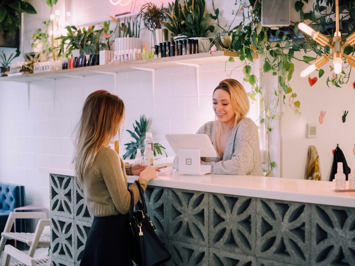 A front desk coordinator smiling as she checks in a client